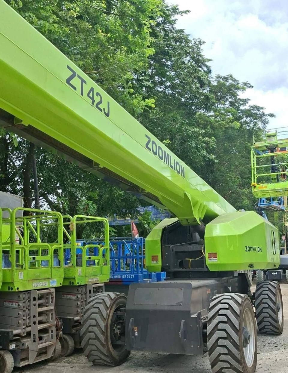 Zoomlion ZT42J, boom lift teleskopik hijau cerah dengan ban off-road besar di area terbuka.